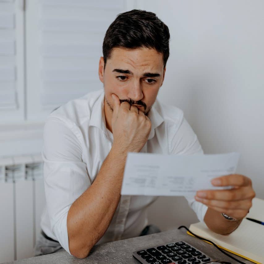 A worried mid-adult man stares at the electricity bill in front of him and wonders if he will have enough money to pay for everything