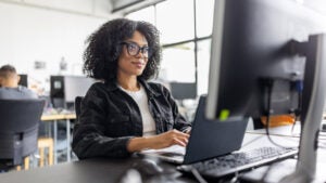 woman sitting at desk in office looking at her computer