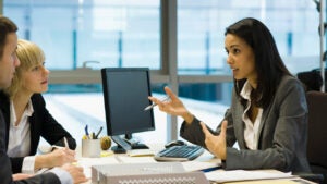 Couple talking to woman across a desk in an office
