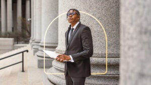 A Black man stands in front of a column