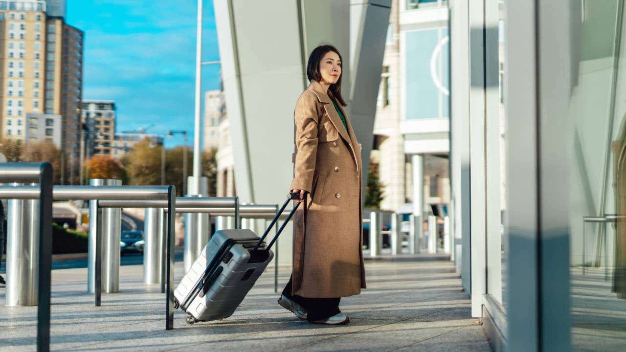 Young Asian business woman with suitcase arriving airport