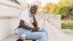 Portrait of African Student Girl wearing muslim hijab sitting on University staircase smiling at camera