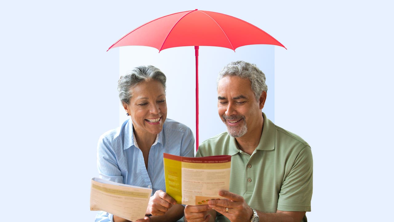 Mature couple reading a document under an umbrella alluding to life insurance protection