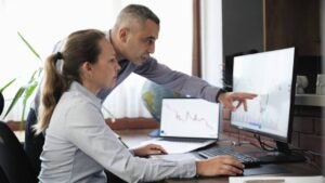 Businesspeople working in an office on financial data using desktop computer.