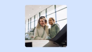 A smiling woman and her daughter look in at a car. There is an illustrated blue background.