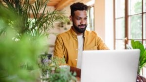 Young man with laptop and coffee working indoors
