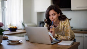 Young woman using a laptop while working from home - stock photo