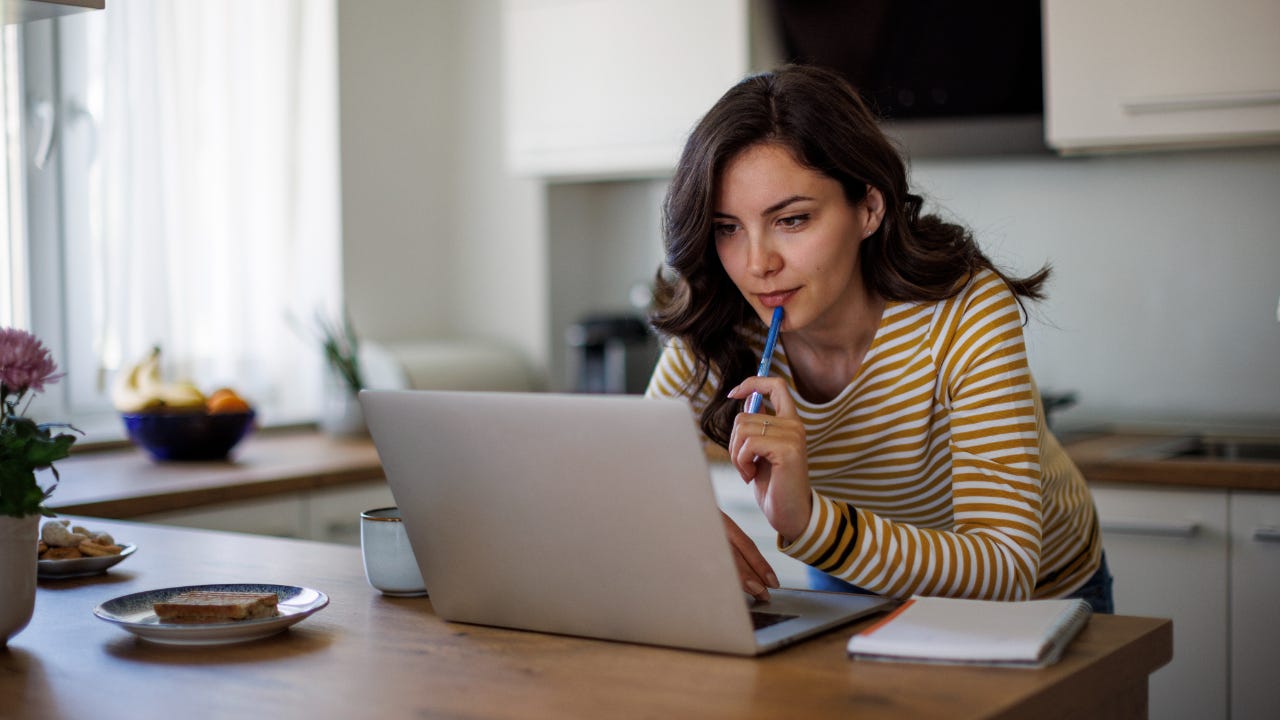 Young woman using a laptop while working from home - stock photo
