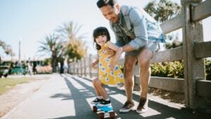 Dad helps young daughter ride skateboard, Father's Day tax tips