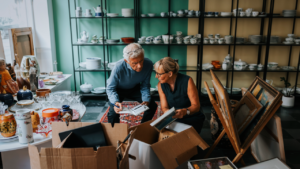 An older couple opens boxes of inventory as they set up their small shop.