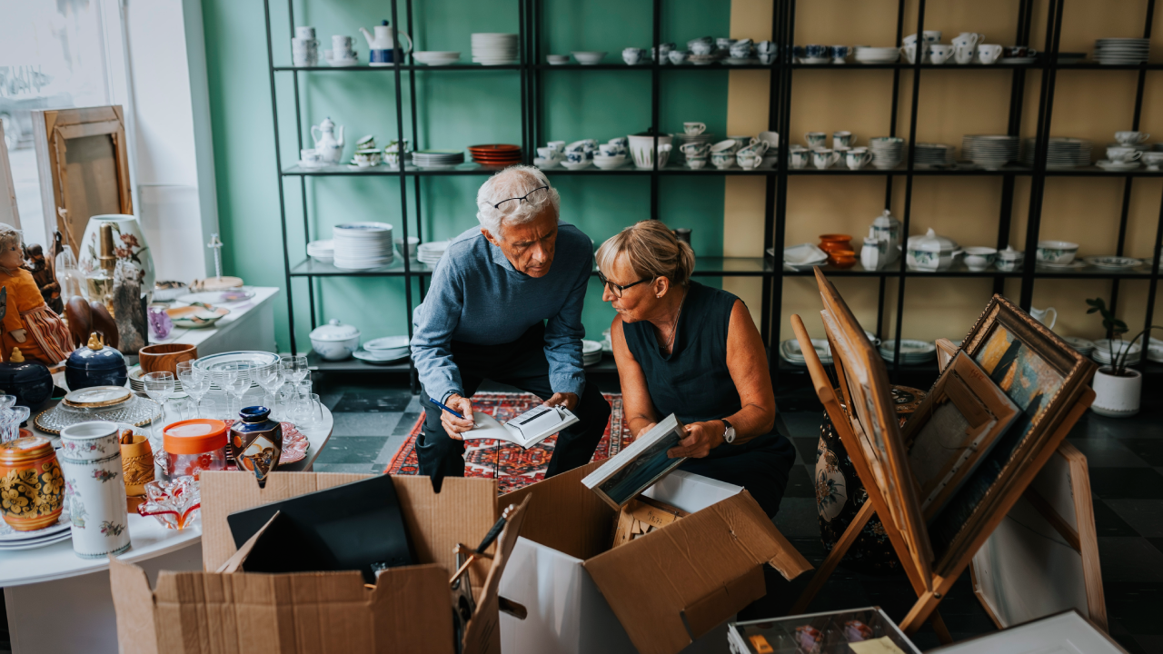 An older couple opens boxes of inventory as they set up their small shop.