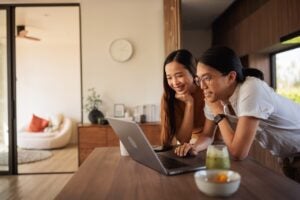 smiling asian couple looking at laptop in kitchen