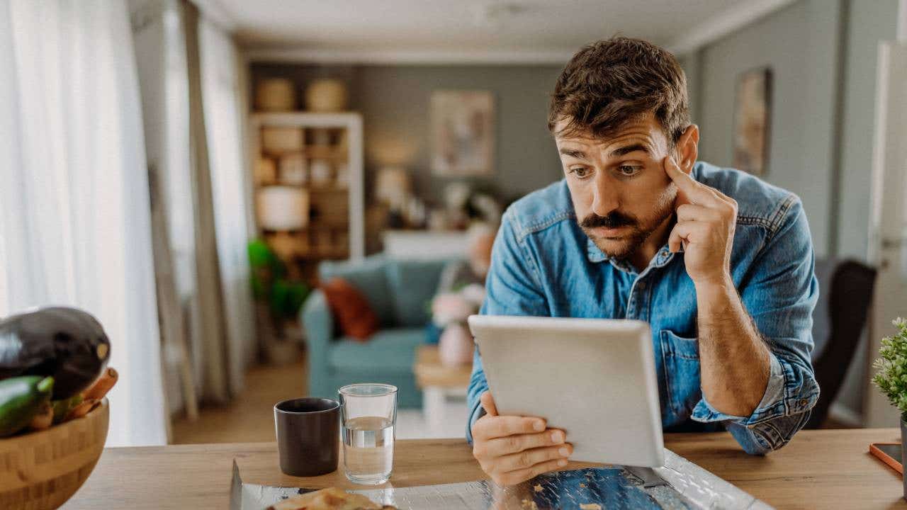 A man who looks worried stares at his table at the kitchen counter.