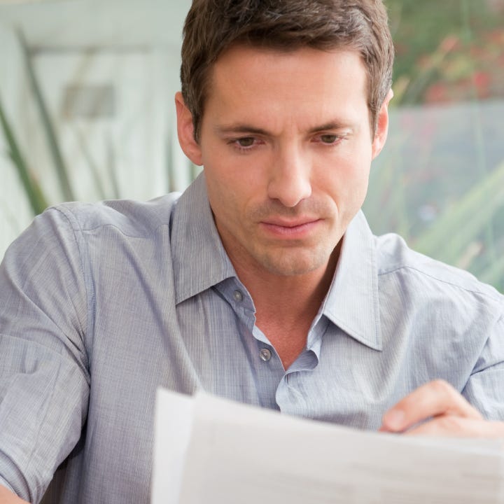 Young white man thoughtfully reviewing document.