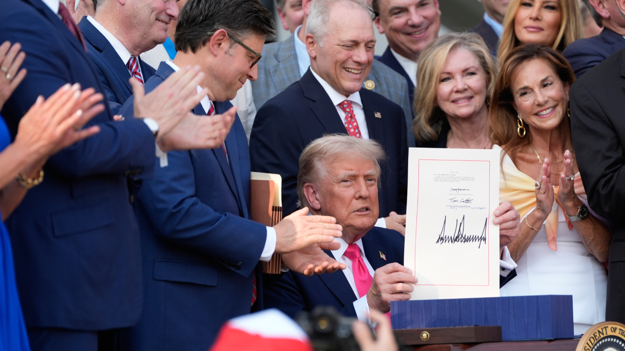 President Donald Trump holds up the "One, Big Beautiful Bill" Act that was signed into law during an Independence Day military family picnic.