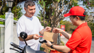 A delivery person delivers food to a customer's house.