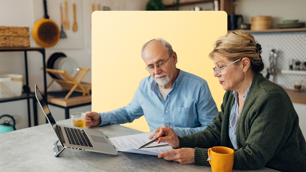 An older couple look at a laptop computer and documents to review their retirement plan.