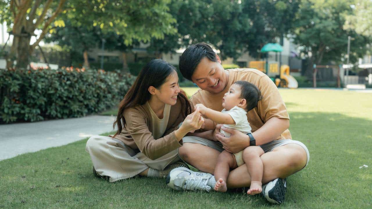 Couple holding a baby in a park.