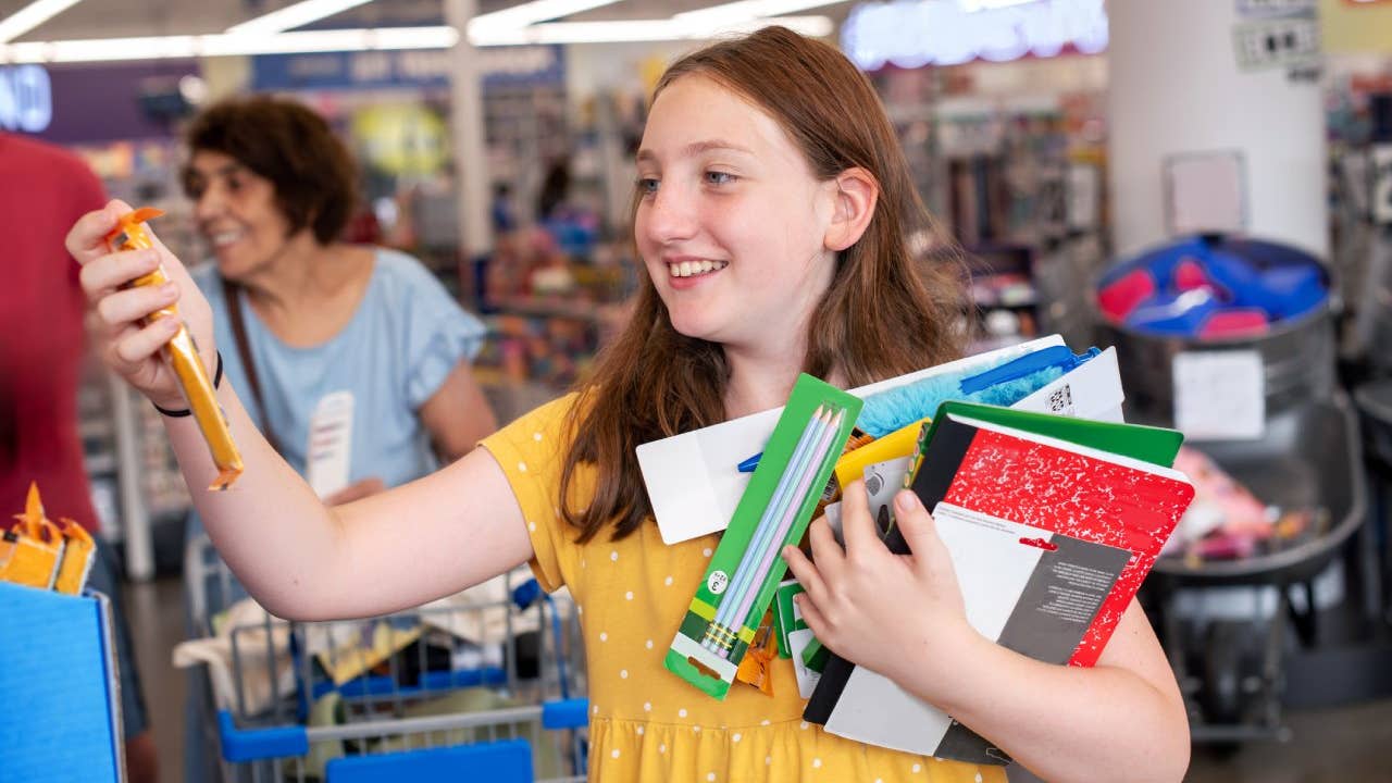 Enthusiastic elementary student examines pencil while grandmother watches during Pennsylvania school supply shopping.
