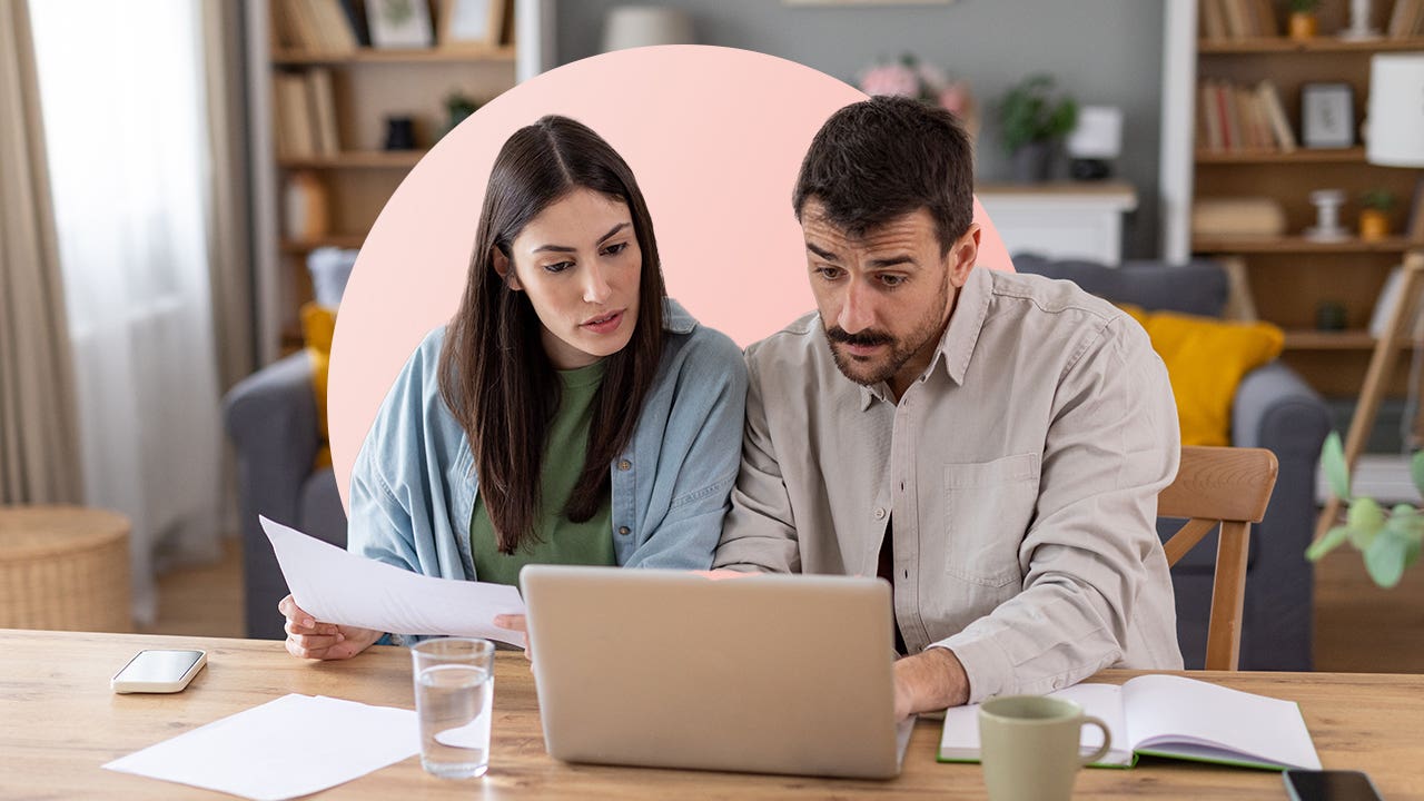 A couple reviews financial documents at a laptop.