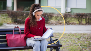 A college student sits on a bench and looks at her binder