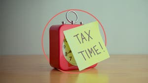 Illustration of a clock with a post-it note on it that says "tax time!"
