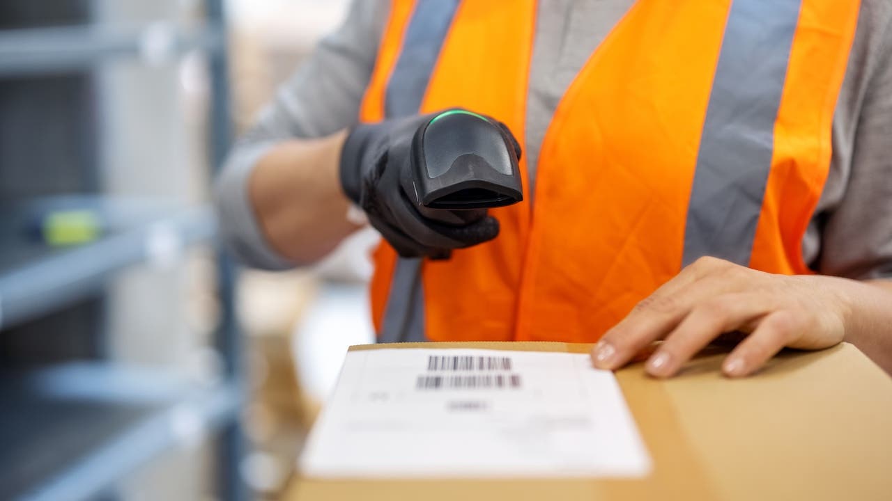 Close-up of a woman warehouse worker scanning package with bar code scanner