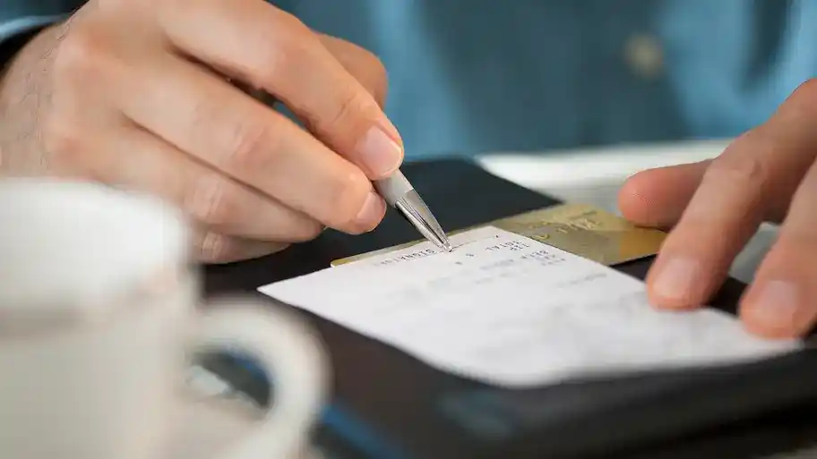 A close up of a person signing a bill